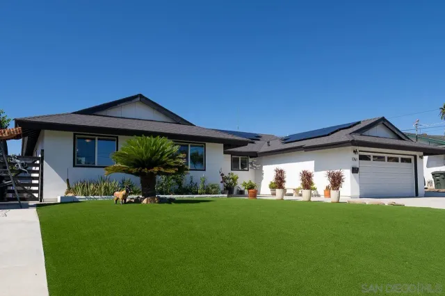 a front view of a house with a garden and trees