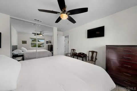 a bedroom with a bed a flat screen tv and a dresser