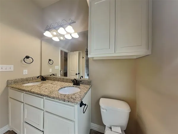 a bathroom with a granite countertop toilet sink and mirror