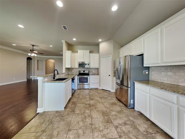 a large kitchen with a large counter top appliances and cabinets