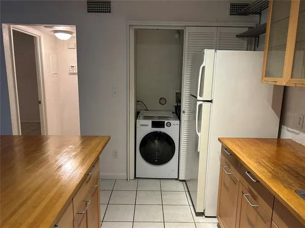 a view of a refrigerator in kitchen and an empty room