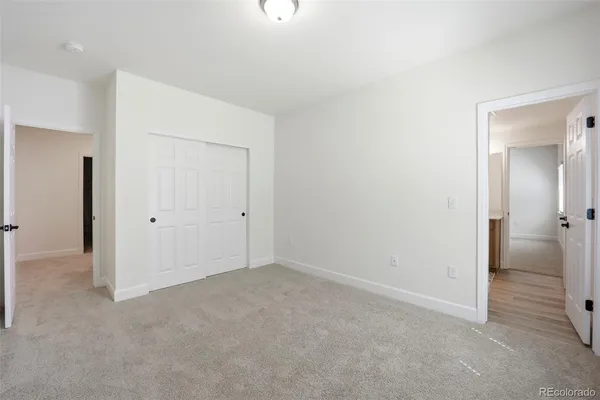 a view of an empty room with closet and a bathroom