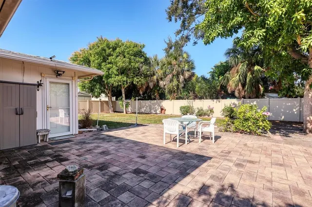 a view of a backyard with large trees and wooden fence