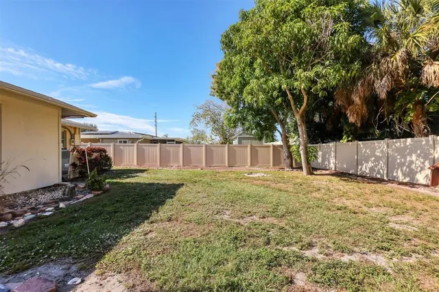 a backyard of a house with table and chairs plants and large tree