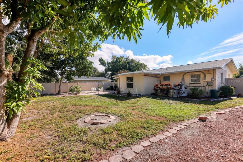 3621 Glen Ridge Lane Sarasota, FL 34233 - Photo 30 of 36 a backyard of a house with table and chairs plants and large tree