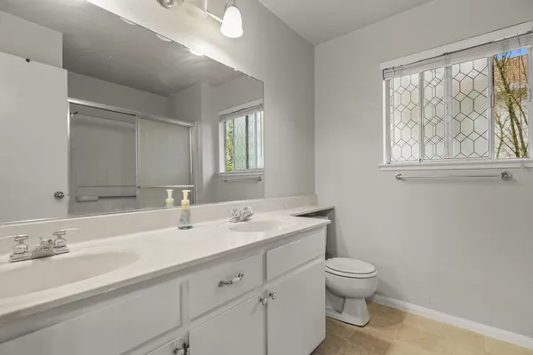 a bathroom with a granite countertop toilet a sink a mirror and a window