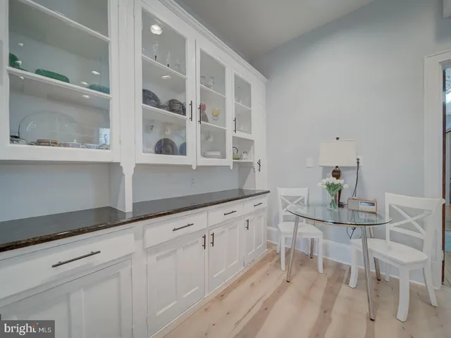 a view of a refrigerator in kitchen and an empty room with wooden floor