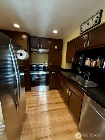 a kitchen with stainless steel appliances granite countertop a stove a sink and a microwave
