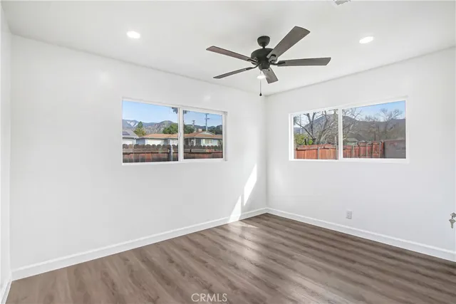 a view of a big room with wooden floor and windows