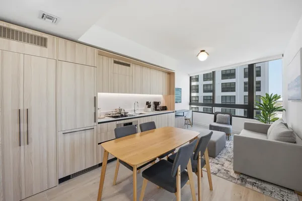 a kitchen with stainless steel appliances a table chairs in it and wooden floors