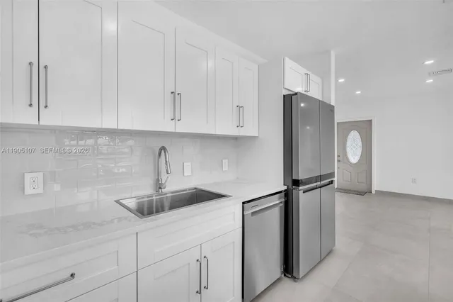 a kitchen with stainless steel appliances granite countertop white cabinets and a refrigerator
