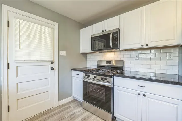 a kitchen with white cabinets and appliances