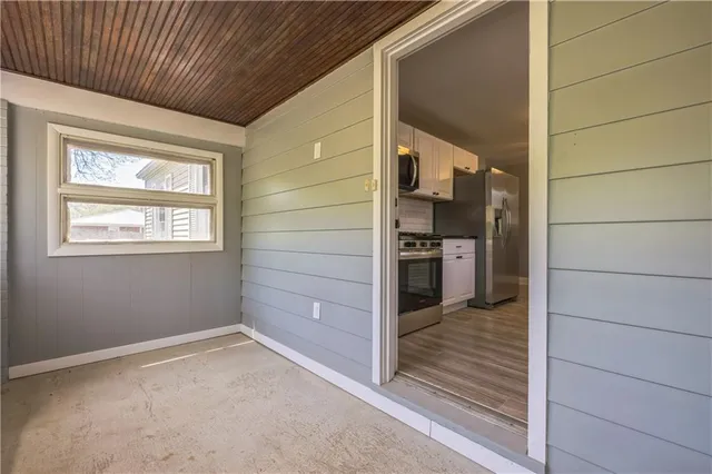 a view of a hallway with wooden floor and a kitchen
