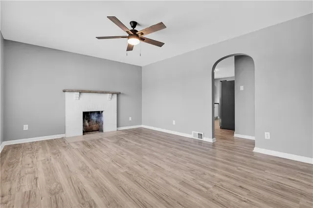 a view of an empty room with wooden floor and a fireplace