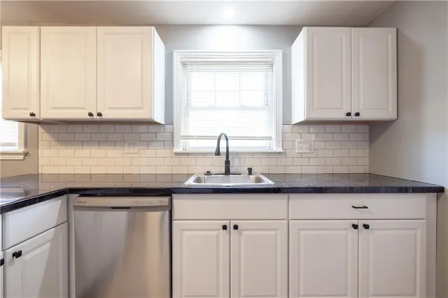 a kitchen with granite countertop white cabinets and a sink