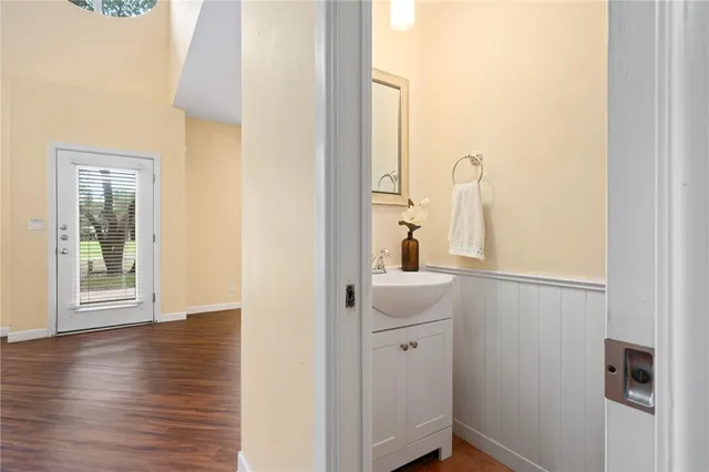 a view of a hallway with wooden floor and a bathroom