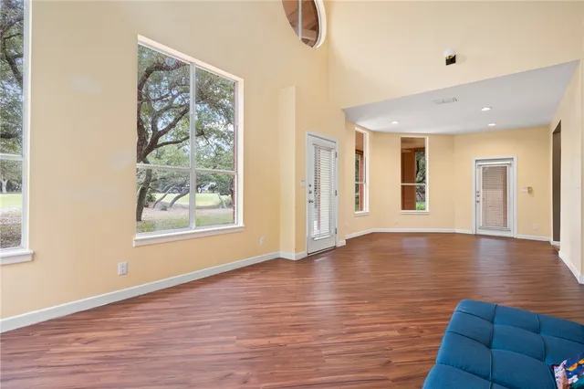 a view of an empty room with window and wooden floor