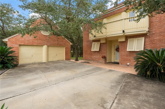 a view of a white house with a large tree