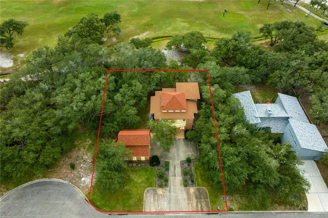 an aerial view of residential house with outdoor space and trees all around