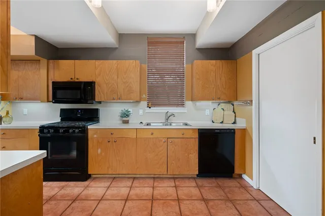 a kitchen with granite countertop a stove top oven a sink dishwasher and a refrigerator