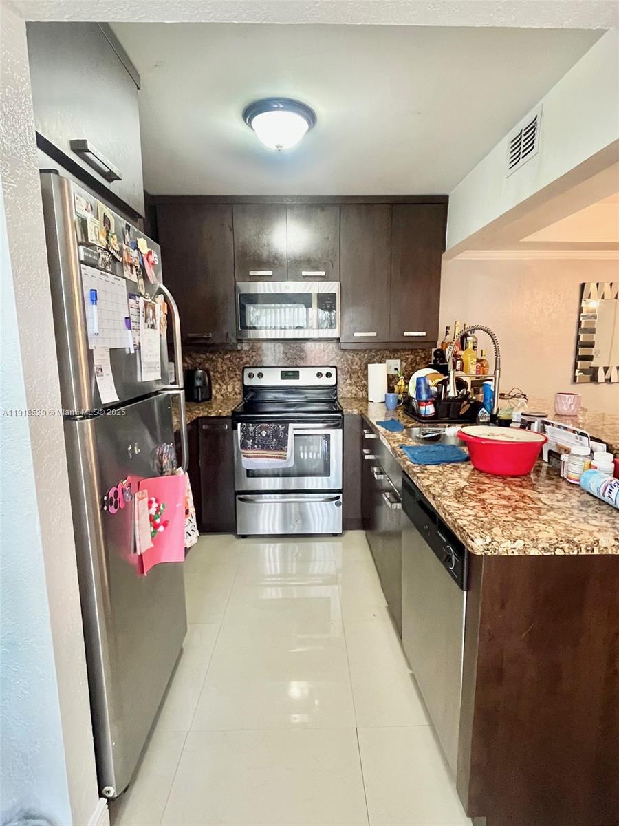 1990 Southwest 121st Court, Unit 232 Miami, FL 33175 - Photo 11 of 28 a kitchen with granite countertop kitchen island stainless steel appliances a sink stove and refrigerator