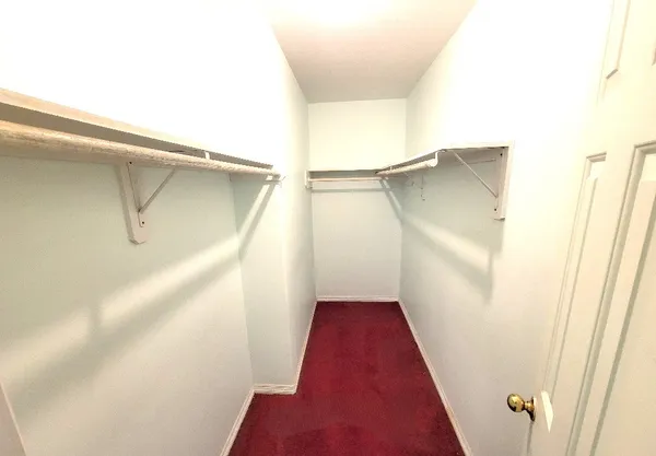 a view of walk in closet with clothes and white walls