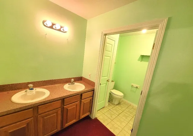 a bathroom with a granite countertop sink toilet and a mirror
