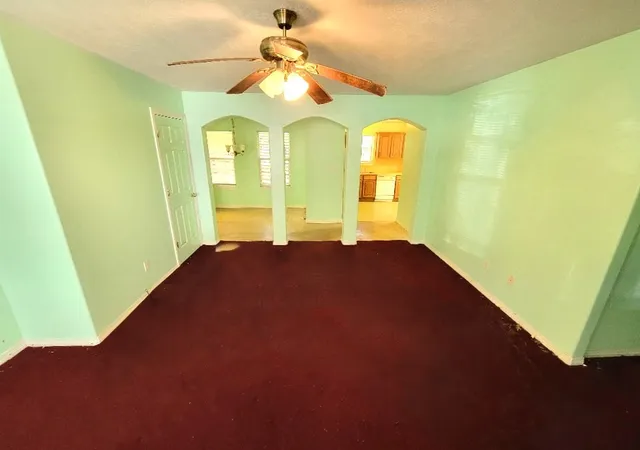 a view of a big room with windows and chandelier fan