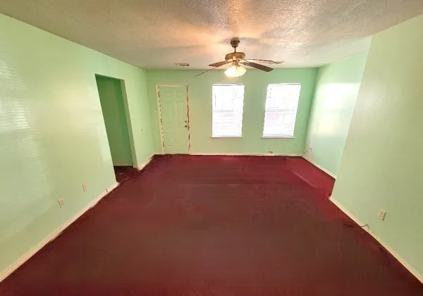 a view of an empty room with a chandelier fan and a window