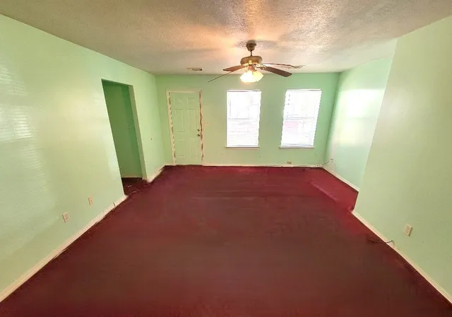 a view of an empty room with a chandelier fan and a window