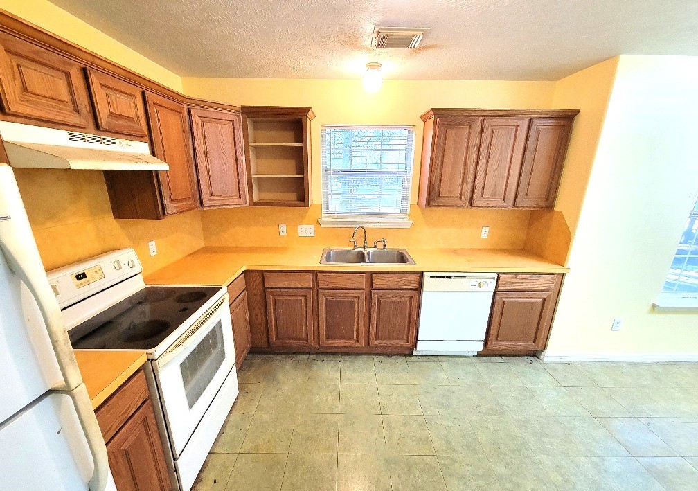 1801 Coe Road Pinehurst, TX 77362 - Photo 6 of 26 a kitchen with stainless steel appliances a stove a sink and a microwave