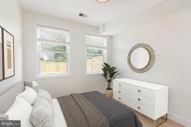 a bedroom with a bed and a potted plant on the dresser