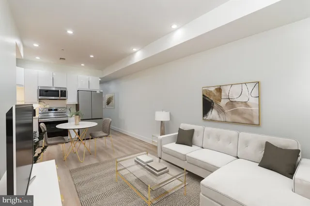 a living room with furniture a flat screen tv and kitchen view