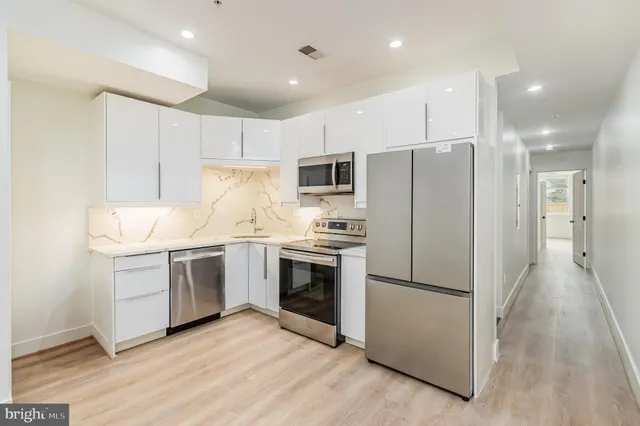 a kitchen with a sink stainless steel appliances and white cabinets