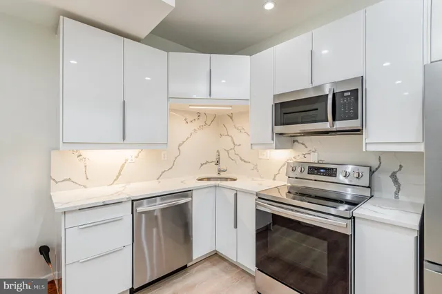 a kitchen with granite countertop white cabinets and stainless steel appliances