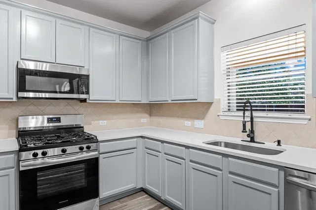 a kitchen with stainless steel appliances granite countertop a sink a stove and microwave
