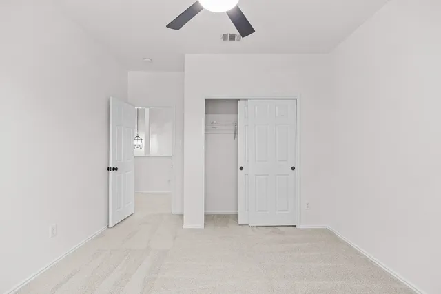 an empty room with ceiling fan and window