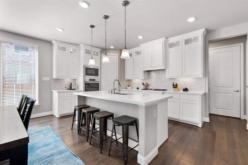 6309 Hall Road Frisco, TX 75034 - Photo 11 of 35 Kitchen featuring glass insert cabinets, a breakfast bar, decorative light fixtures, a center island with sink, and white cabinets