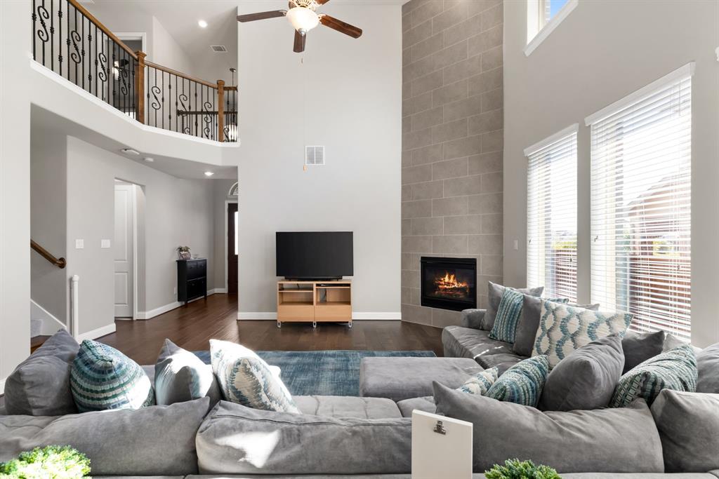 6309 Hall Road Frisco, TX 75034 - Photo 9 of 35 Living room featuring a tile fireplace, a high ceiling, wood finished floors, stairway, and ceiling fan