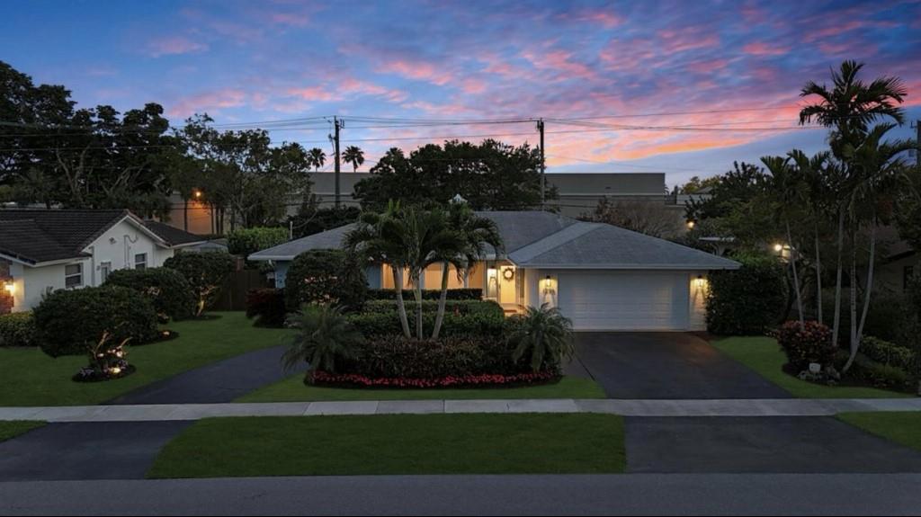 a view of a white house next to a yard with big trees