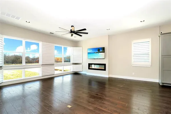 a view of an empty room with a window and wooden floor