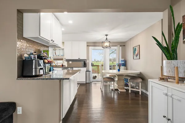 a kitchen with stainless steel appliances granite countertop a stove top oven a sink a dining table and chairs with wooden floor