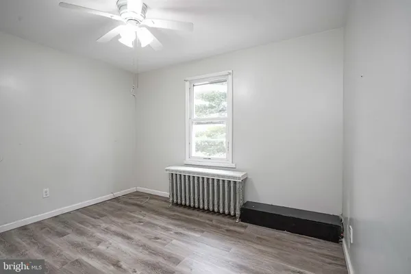 an empty room with wooden floor chandelier fan and windows