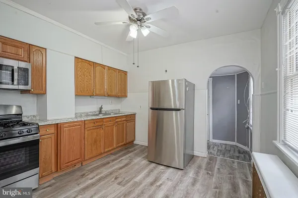 a kitchen with stainless steel appliances granite countertop a refrigerator a stove a sink and a microwave oven with white cabinets