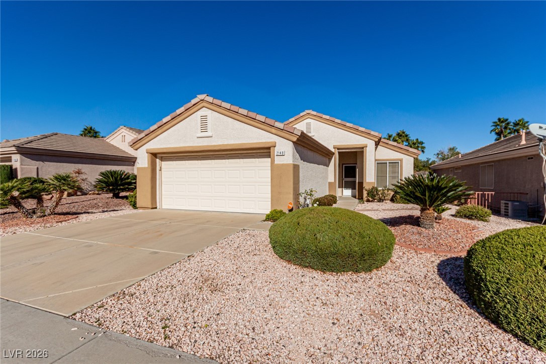 Single story home with concrete driveway, stucco siding, a garage, and a tile roof