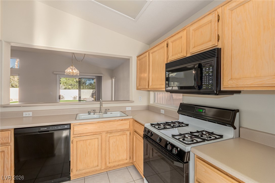2148 Point Mallard Drive Henderson, NV 89012 - Photo 11 of 31 Kitchen featuring black appliances, light brown cabinets, light countertops, and lofted ceiling