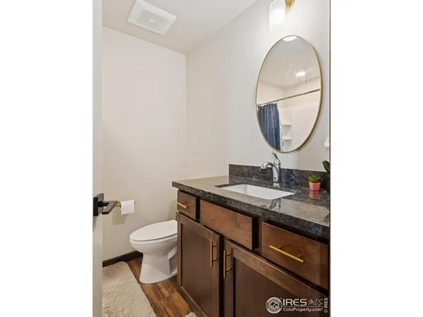 a bathroom with a granite countertop toilet a sink and a mirror