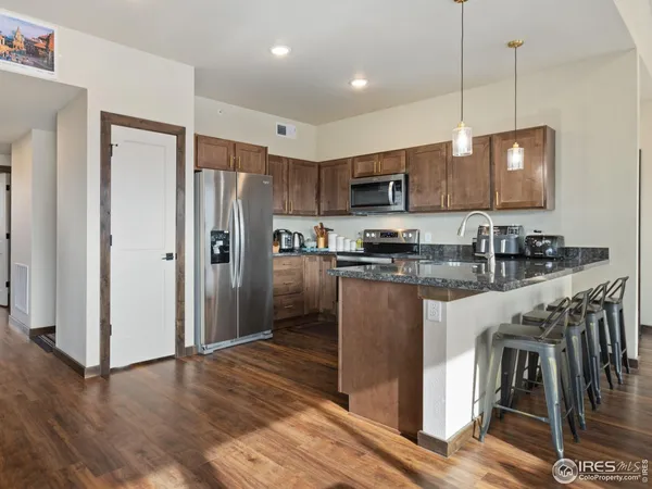a kitchen with kitchen island granite countertop wooden floors stainless steel appliances a sink and a center island