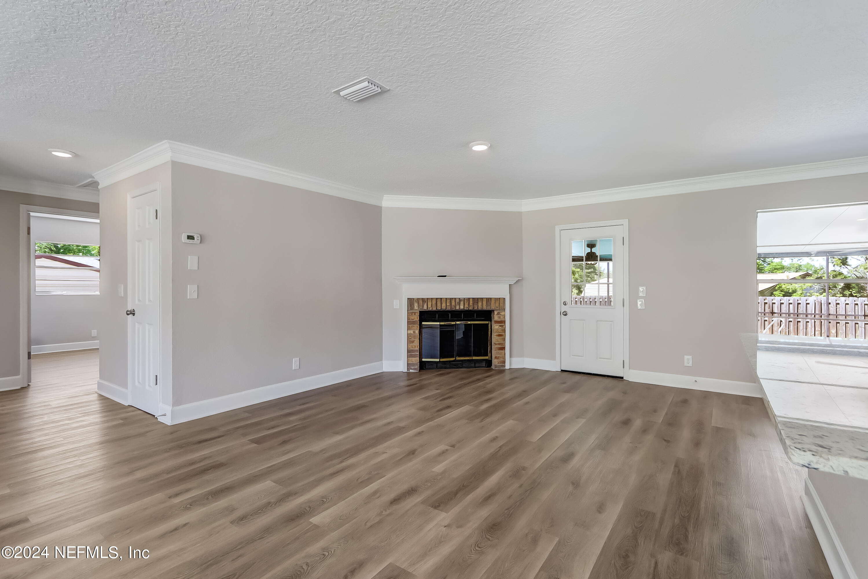 327 Neptune Road Orange Park, FL 32073 - Photo 17 of 40 an empty room with wooden floor fireplace and windows