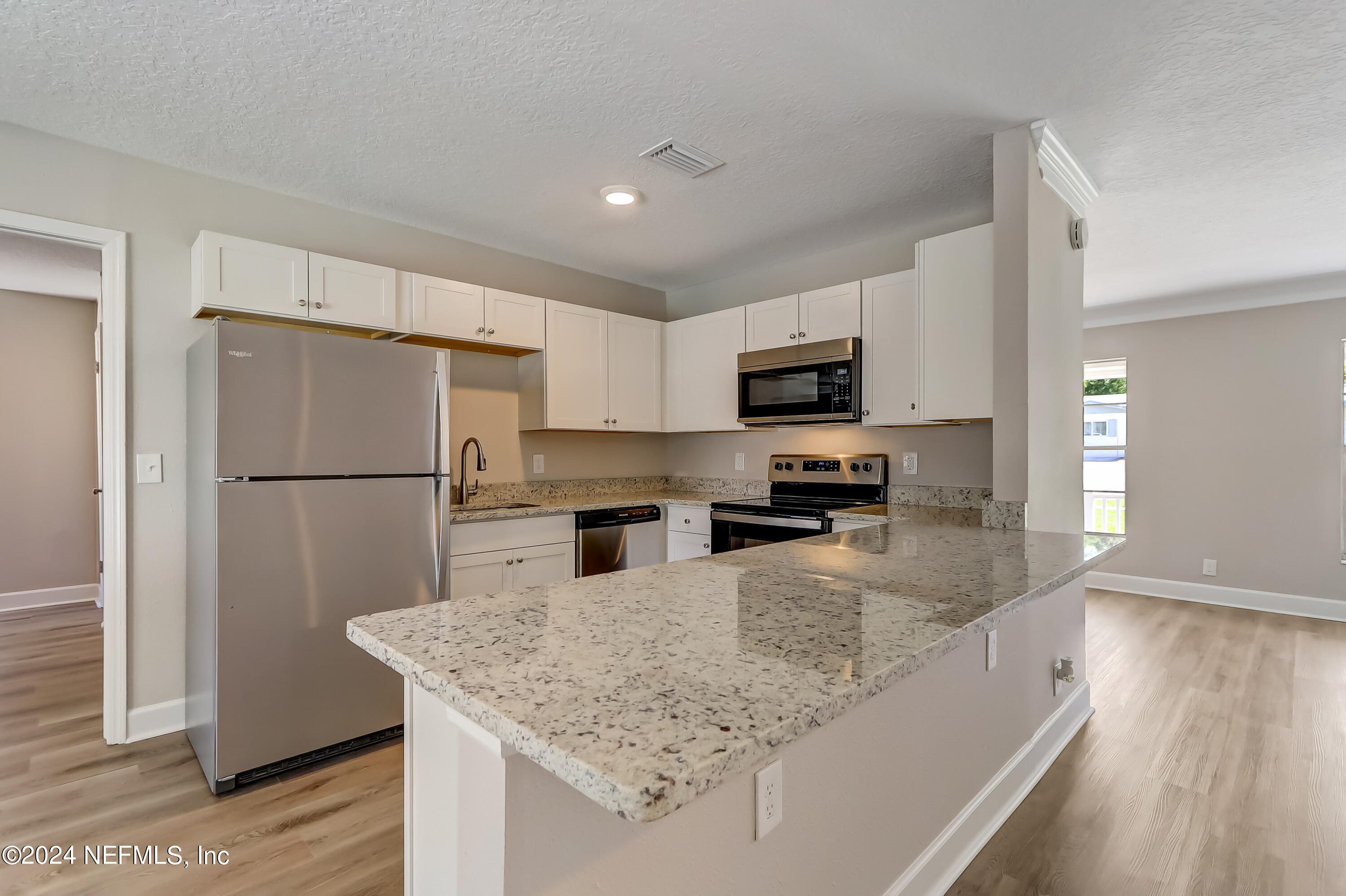 327 Neptune Road Orange Park, FL 32073 - Photo 24 of 40 a kitchen with granite countertop a refrigerator a sink a stove a microwave and wooden floor
